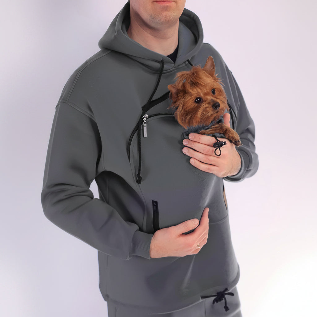 Person wearing a gray hoodie with a front pocket holding a small dog.