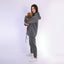 Woman wearing a gray tracksuit holding a small dog on a white background