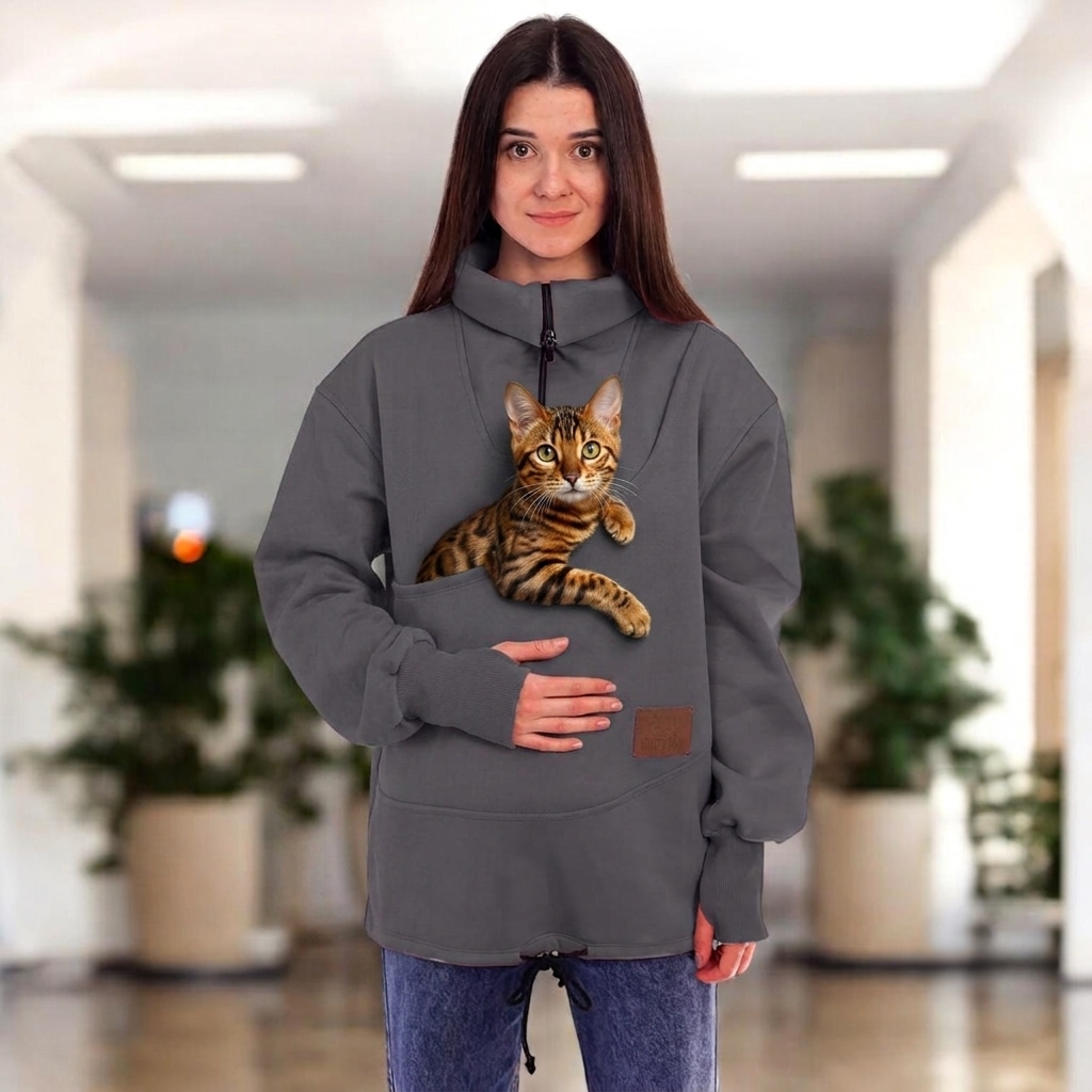 Women wearing a gray sweatshirt with a cat in the pocket on a blurred indoor background