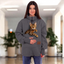 Women wearing a gray sweatshirt with a cat in the pocket on a blurred indoor background