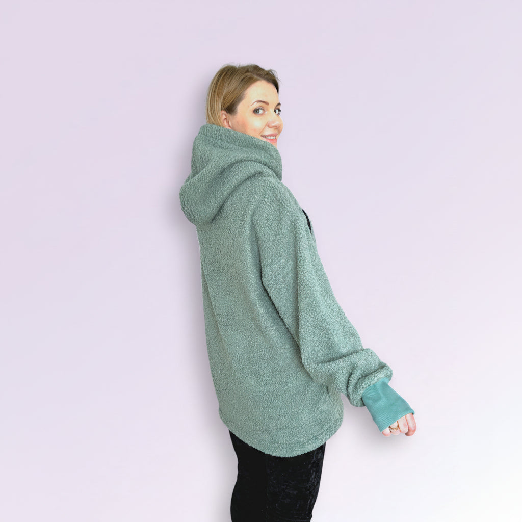 Person wearing a green oversized hoodie on a light purple background