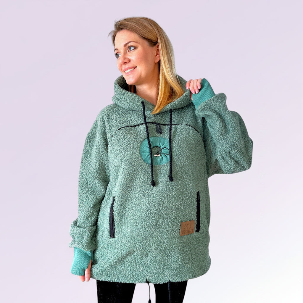 Woman wearing a green fleece hoodie with a hood against a white background