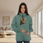 Woman wearing a green sweatshirt with cat in the pouch in a living room 