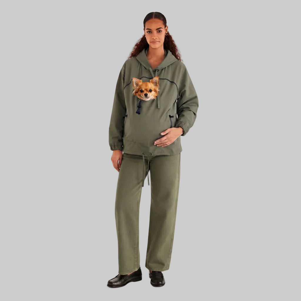 A model wearing an olive green matching loungewear set consisting of a pullover hoodie with a dog face graphic on the chest and matching wide-leg sweatpants, photographed against a light gray studio background.