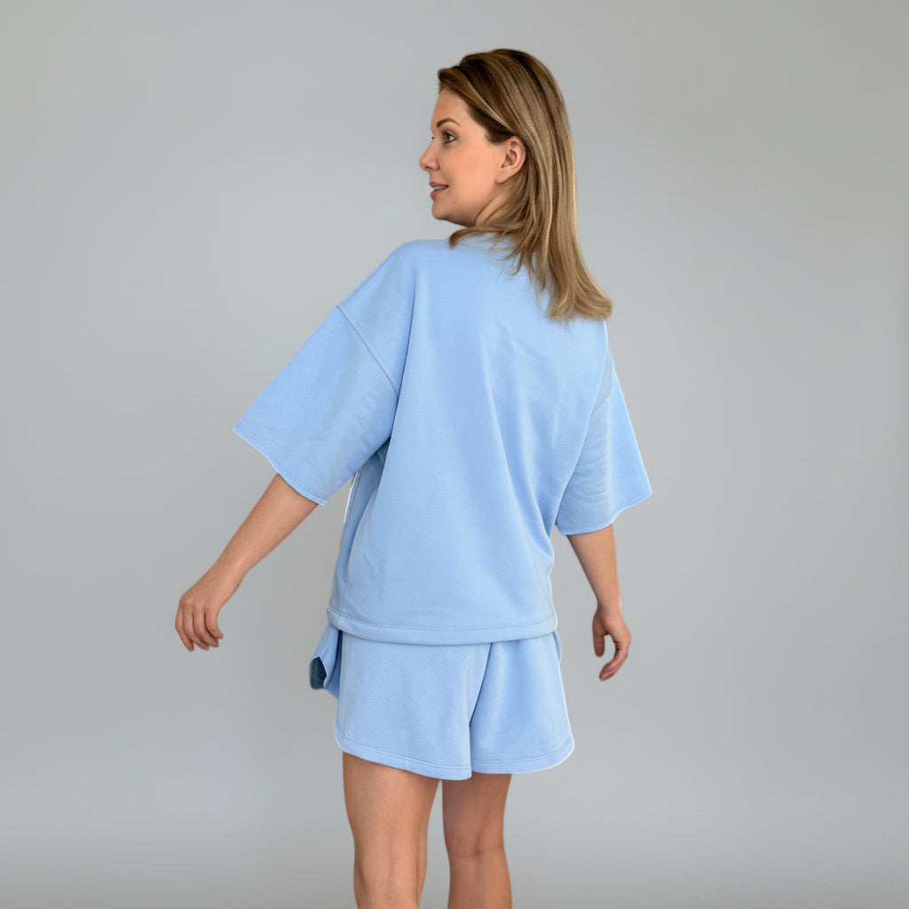 Woman wearing a light blue outfit against a gray background