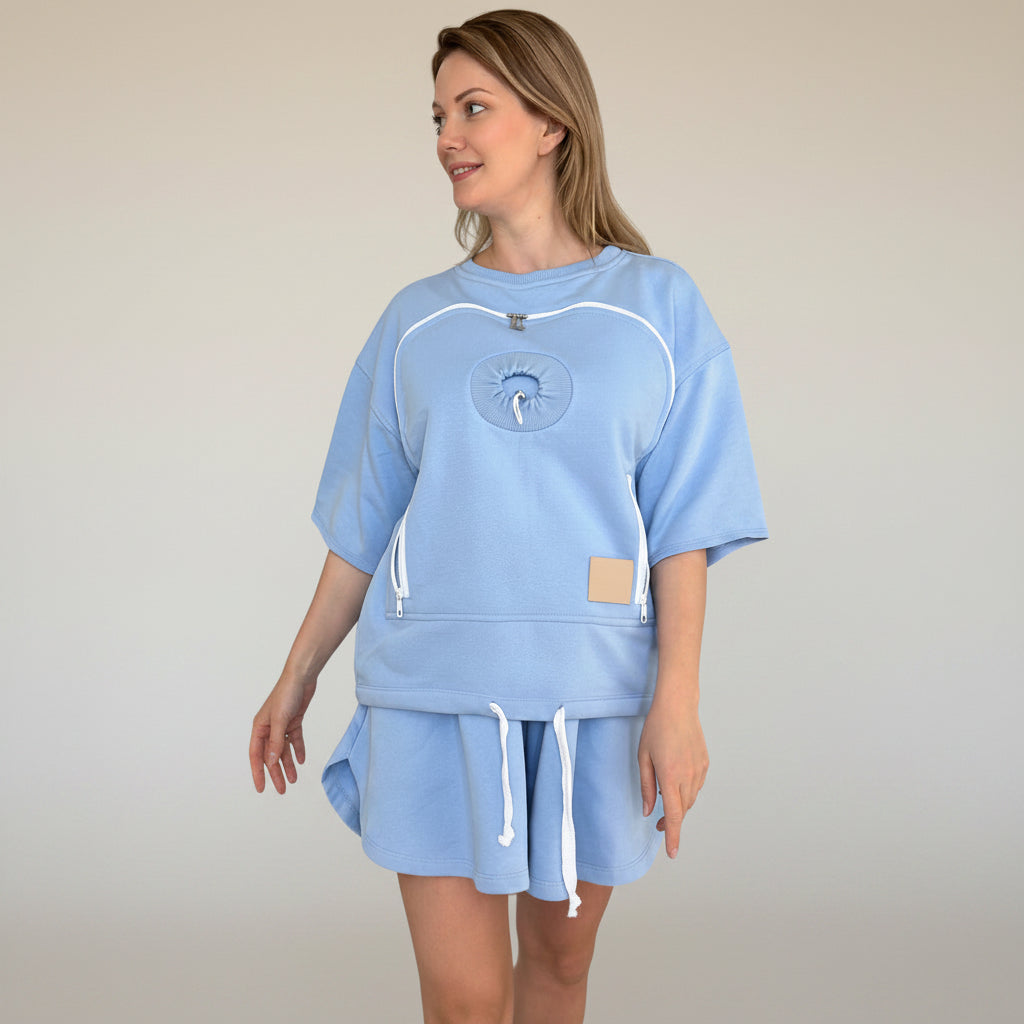 Woman wearing a light blue outfit with a logo on a plain background