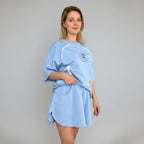 Woman wearing a light blue sweatshirt with a pet hole against a plain background