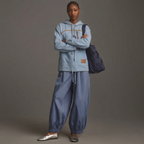 Person wearing a light blue denim hoodie with a pet pouch and an opening for a cat's head, against a dark background.
