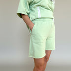 Light green tracksuit with shorts on a plain background