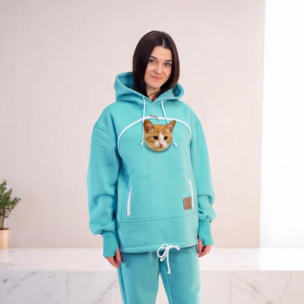 Person wearing a turquoise hoodie and pants set with a cat face design in a room.