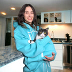 Person wearing a Mint Green hoodie holding a cat in a kitchen