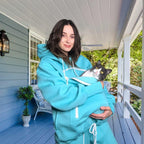 Person in a Mint Green hoodie holding a cat on a porch