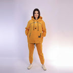 Person wearing a mustard hoodie and jogger set on a white background