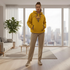 Woman wearing a orange hoodie with a dog peeking out, standing in a modern living room.