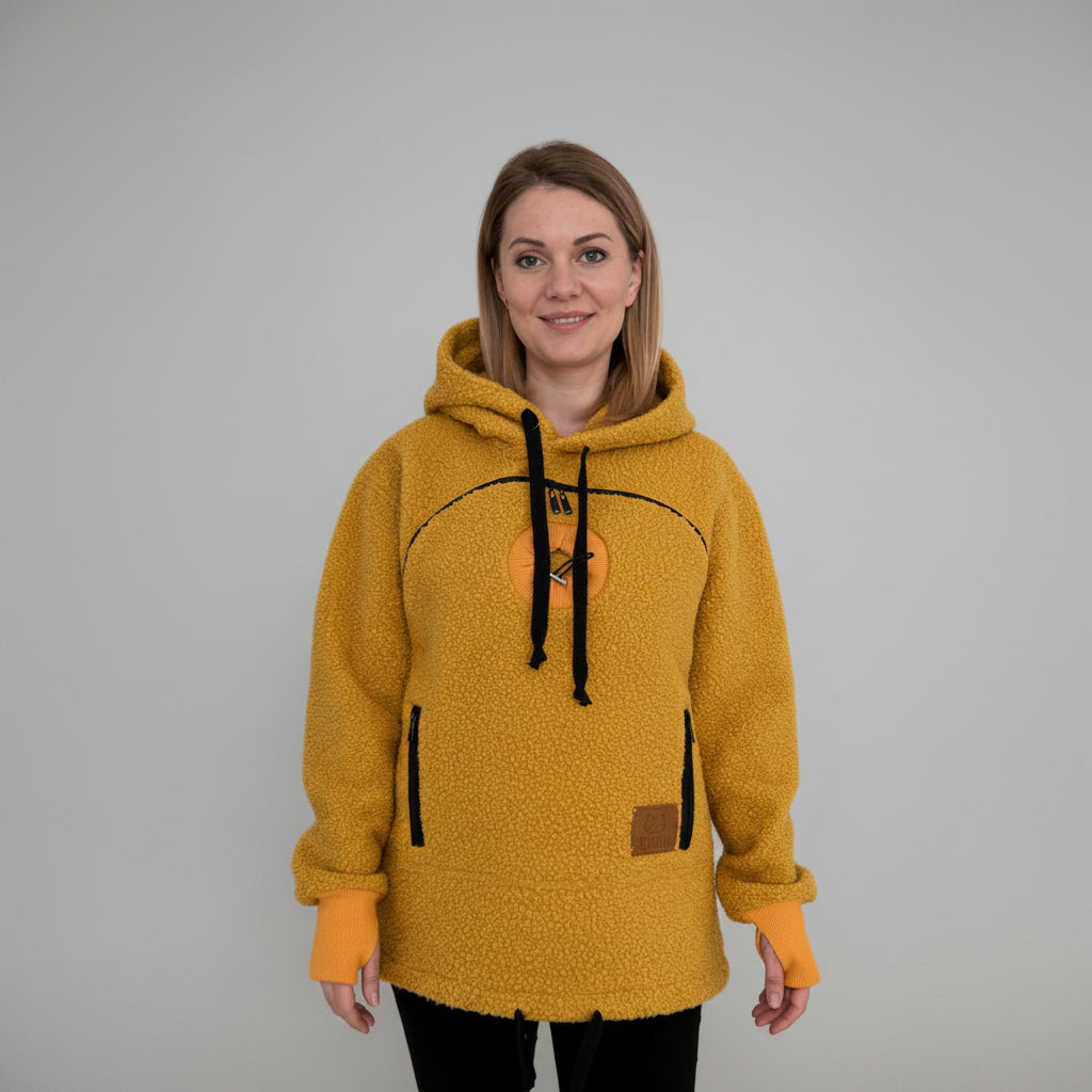 Woman wearing a orange fleece hoodie with black drawstrings in a home setting