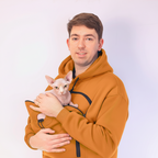 Man holding a small hairless cat  against a plain background