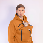 Person wearing a orange hoodie with a hairless cat peeking out from the front pocket against a white background