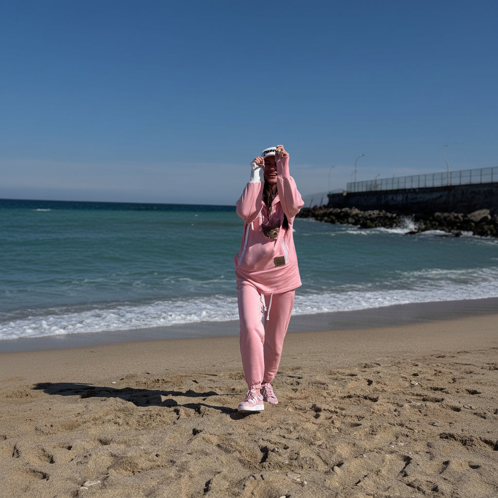 Person in a pink outfit taking a selfie on a beach with ocean and sky in the background