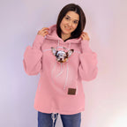 Person wearing a pink hoodie with a dog on a plain background