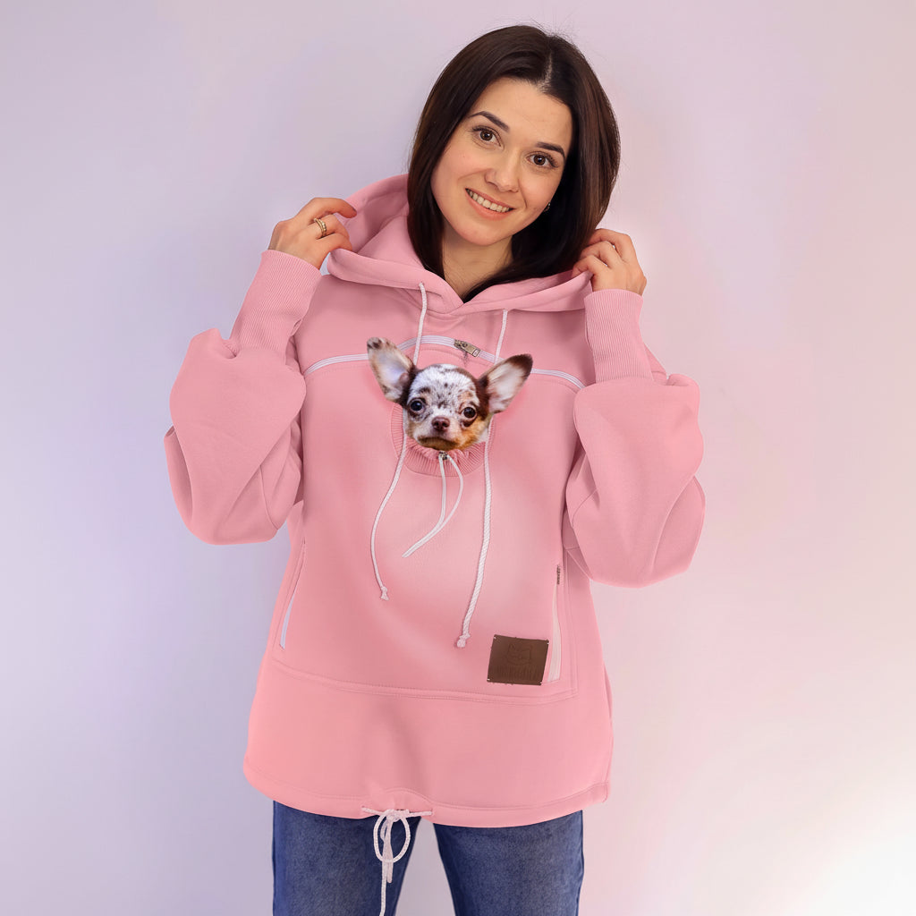 Person wearing a pink hoodie with a dog on a plain background