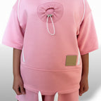 Pink outfit with a unique design on the back against a white background