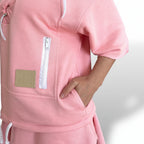 Pink tracksuit with a visible brand logo on a light gray background