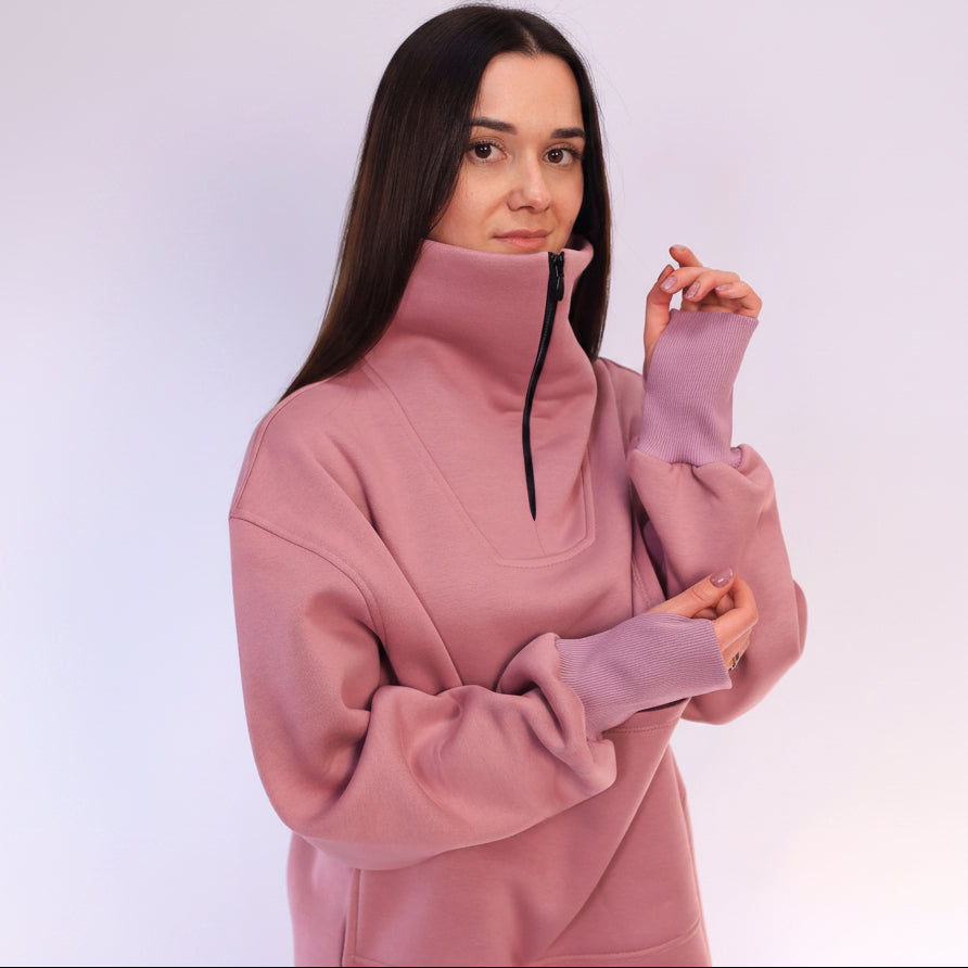 Woman wearing a pink zip-up sweatshirt against a white background