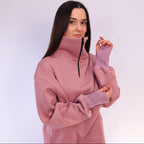 Woman wearing a pink zip-up sweatshirt against a white background