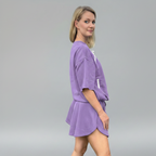 Woman wearing a purple outfit on a gray background