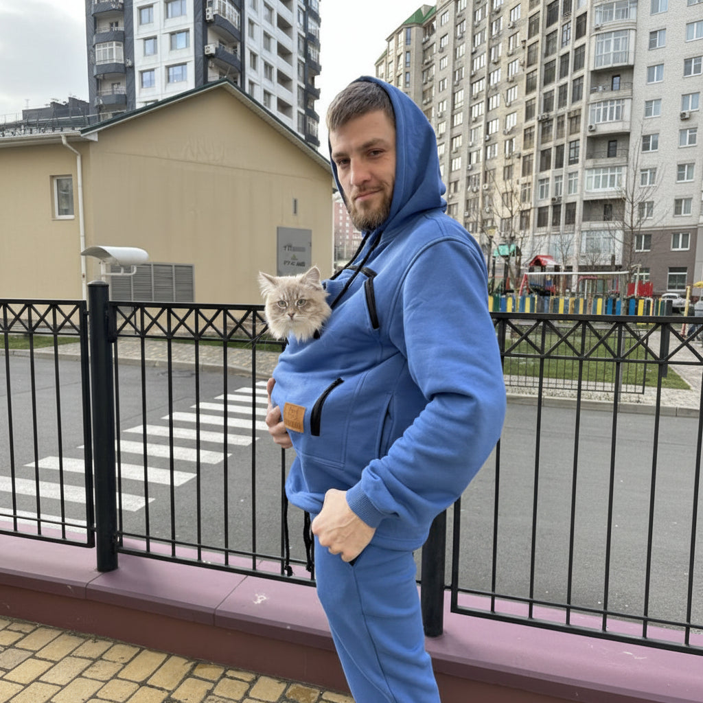 Men wearing a royal blue onesie with a cat inside, standing on a street with buildings in the background.