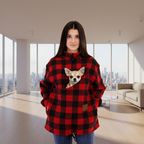 Women wearing a red square plaid sweatshirt with Chihuahua in pouch, standing in living room.