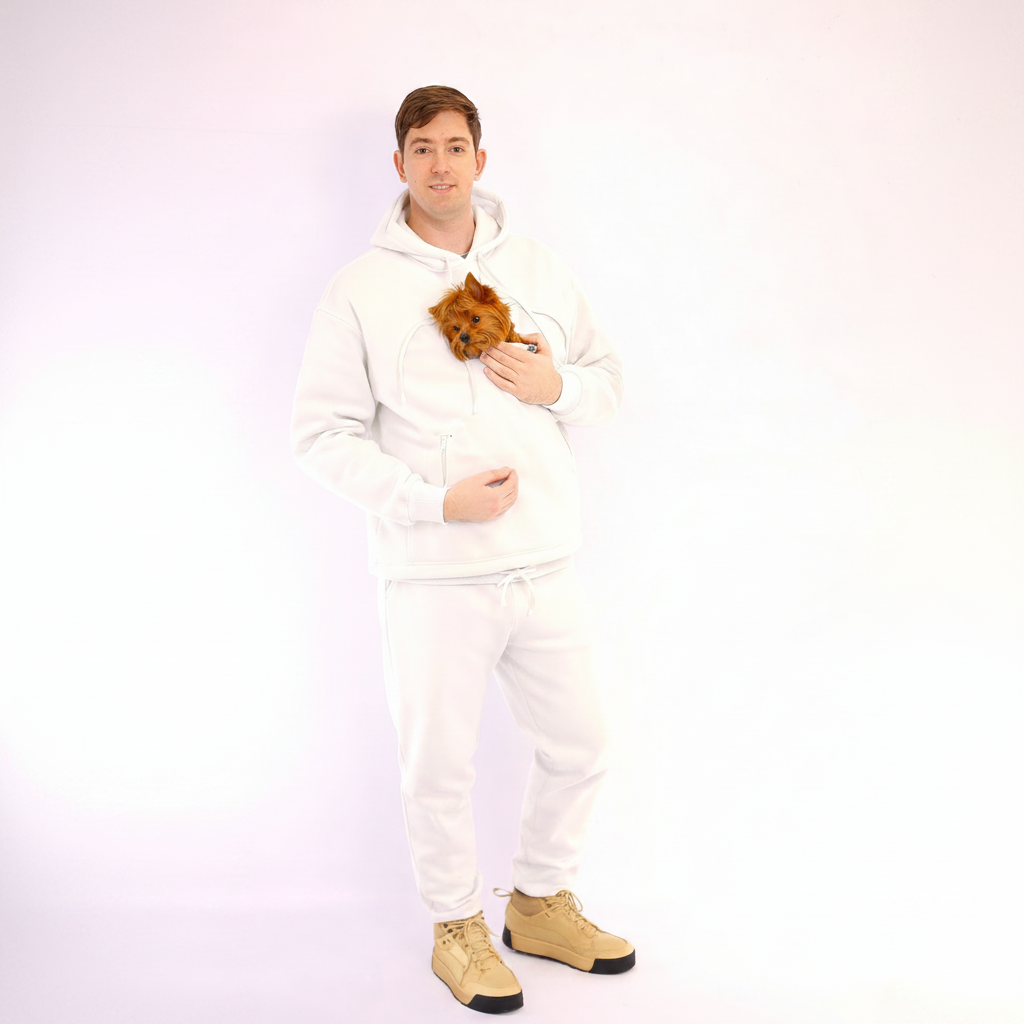 Person wearing a white hoodie and pants holding a small brown dog on a white background