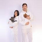 Two people wearing matching white outfits with animals, standing against a plain background.