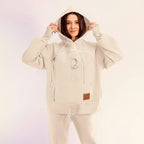 Person wearing a white hoodie and pants on a light pink background