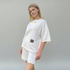 Woman wearing a white outfit with a brown patch on a gray background