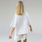 Person wearing a white oversized t-shirt and shorts set on a plain background