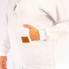Close-up of a hand in a white jacket with a brown patch on a light background