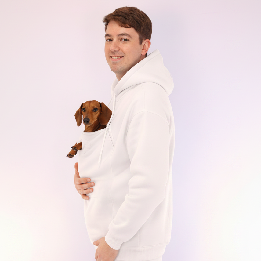Man wearing a white hoodie holding a small dog on a light purple background