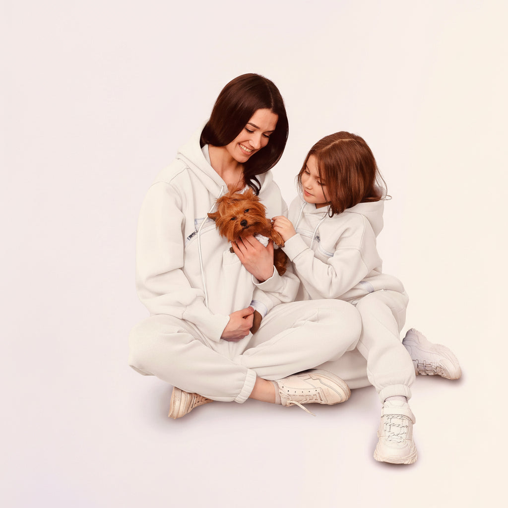 Two people in matching outfits sitting on the floor with a small dog.