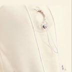 Close-up of a white garment with drawstrings and a hand holding it.