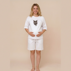 Woman wearing a white t-shirt with a cat and white shorts on a beige background