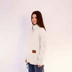 women wearing a white fleece sweatshirt with a brown patch on a light pink background