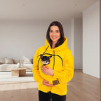 Woman in a yellow hoodie holding a small dog in a living room