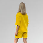 Person wearing a yellow outfit on a plain background