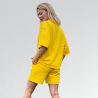 Woman wearing a yellow outfit on a light gray background
