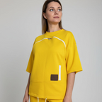 Woman wearing a yellow outfit with a brown pocket on a plain background