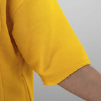 Close-up of a yellow shirt sleeve with a blurred indoor background