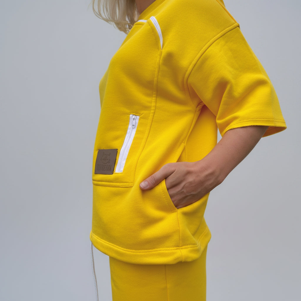 Person wearing a bright yellow outfit with a pocket and visible brand label.