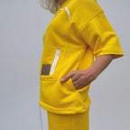 Person wearing a bright yellow outfit with a pocket and visible brand label.
