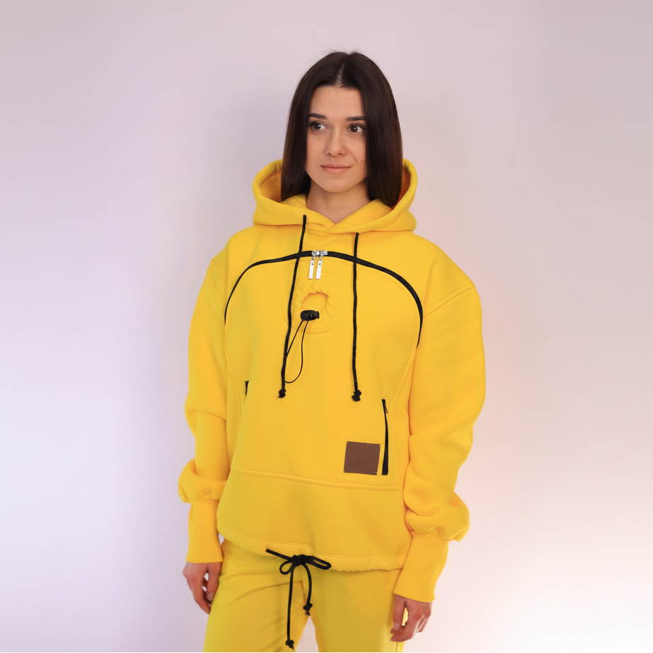 Person wearing a yellow hoodie with black drawstrings on a light purple background